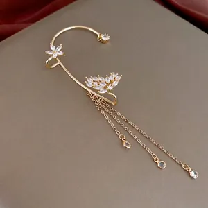Goldene Schmetterlings-Ohrklemme mit Zirkon-Quasten auf Lederhintergrund