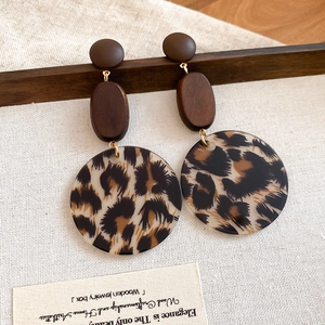 Details von Retro-Ohrringen mit Leopardenmuster aus Acryl und Holz auf Leinenhintergrund