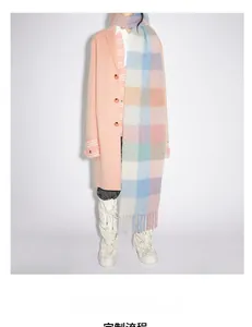 Détail d'une écharpe à carreaux douce avec franges sur un mannequin en manteau rose