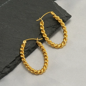 Polished 18k gold twisted hoop earrings displayed on black slate with silk fabric