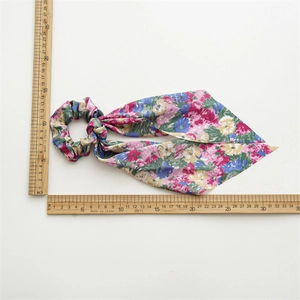 Pink floral tie-dye scrunchie with long ribbon tails shown with size measurement scale