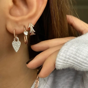Rose gold heart and tree earring set with zircons shown on a model's ear