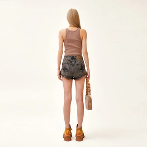 Rückansicht eines Models in bestickten Denim-Shorts mit braunem Tanktop und Stiefeln
