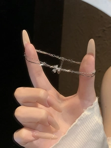 Close-up of silver double-layered bracelet with a delicate bow charm and metal beads