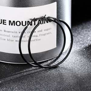Close-up of minimalist black hoop earrings on a textured surface with metallic accents