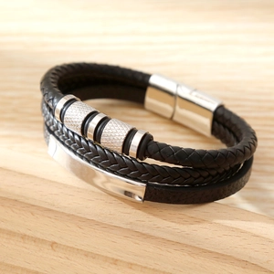 Close-up of multilayer black woven leather bracelet with silver magnetic buckle on wood