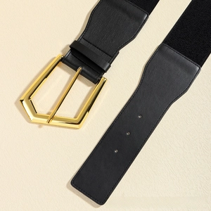 Detailed close-up of a wide elastic belt with a golden geometric buckle and black faux leather