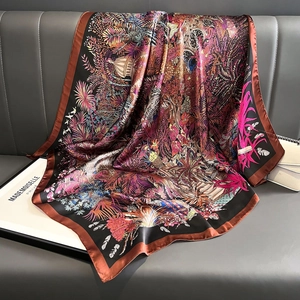 Satin silk scarf with floral and architectural patterns draped on a leather sofa