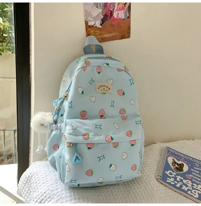 Detail of light blue strawberry backpack with white pom-pom and heart star pattern