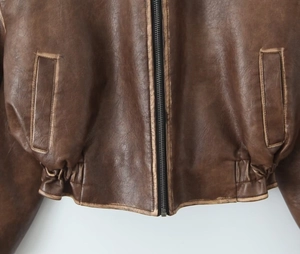 Détail d'une veste vintage en cuir PU marron avec fermeture éclair et ourlet élastique