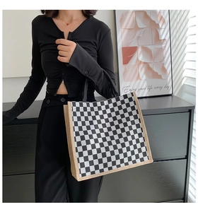 Detail of checkerboard tote bag with woven trim and handles in modern natural lighting