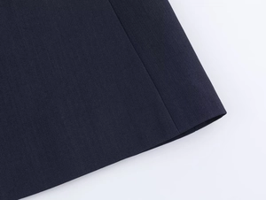 Detailed close-up of stitching and hem on navy blue fashion suit jacket and trousers
