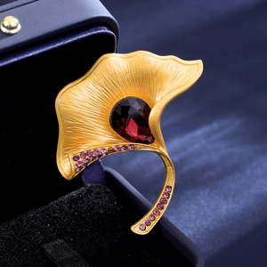 Elegant gold ginkgo leaf brooch with teardrop red gemstone in a premium jewelry box