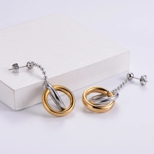 Detail of two-tone gold and silver circular drop earrings on a minimalist white stand