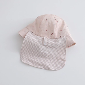 Détail d'un chapeau de soleil en coton rose avec broderie fraise et protège-nuque à carreaux