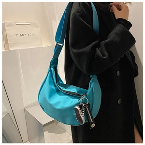 Detail of turquoise oxford cloth dumpling bag with sneaker charm and woven strap