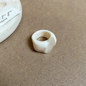 Detailed top view of a cream oval resin ring on minimalist kraft paper background