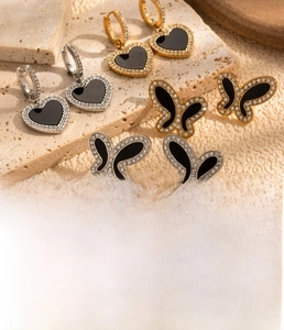 Détail de boucles d'oreilles en titane avec papillon en émail noir et zircons incrustés