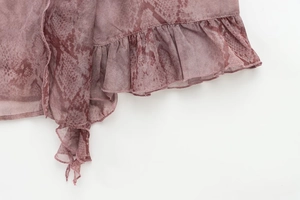 Detailed close-up of purple snakeskin print chiffon fabric with ruffled edge design