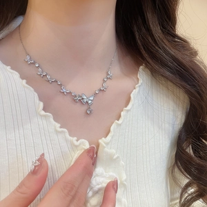 Close-up of silver butterfly pendant necklace with cubic zirconia worn by model