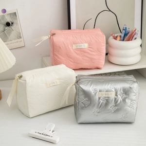 Quilted waterproof PU makeup bags in pink, beige, and silver with bow patterns and ribbons