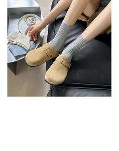 Detail of yellow suede clogs with adjustable metal buckle worn over grey knit socks