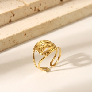 Detail shot of golden irregular hollow knotted ring on a minimalist stone background
