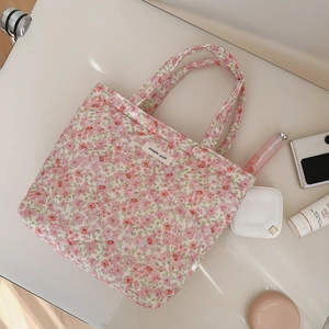 Quilted floral handbag with cute flower pattern and brand label on a white surface