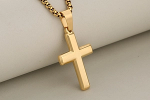 Close-up of a polished golden cross pendant with a matching sleek box chain design