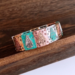 Detail of vintage stretch bracelet with pine and snowflake motifs on turquoise metal tiles