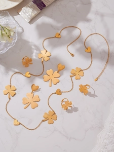 Flat lay of gold brushed clover jewelry set with long chain earrings and rings
