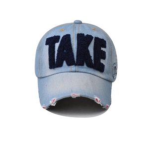 Macro detail of 3D navy TAKE embroidery and distressed brim on light blue denim cap