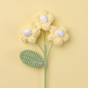 Detailed view of three handmade crochet yellow flowers with green leaf on soft background