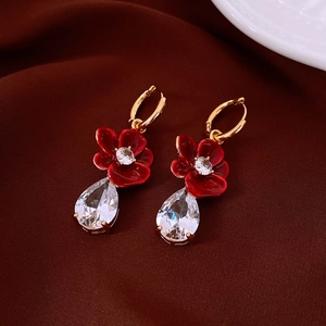 Detailed macro view of 18k gold flower earrings with red enamel and teardrop zircon