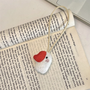 Close-up of cute plush duck charm with red hat on a vintage book background