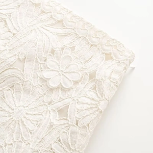 Close-up of white floral lace embroidery texture and invisible zipper on the skirt