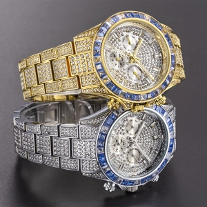 Close-up of gold and silver iced-out luxury watches with blue gem bezels on black surface