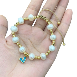 Close-up of pearl and gold bead bracelet featuring a blue gemstone heart pendant