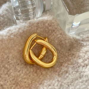 Polished gold U-shaped silver earrings displayed on a soft beige knitted fabric
