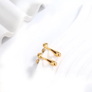 Close-up of golden teardrop earrings with a fluid liquid metal texture and mirror finish