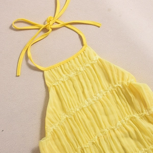 Close-up of bright yellow halter top with tiered ruffles and breathable pleated fabric