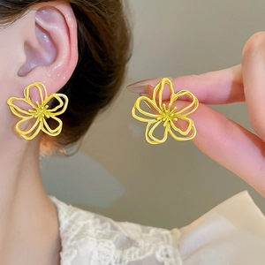 Nahaufnahme gelber hohler Blumenohrringe, getragen und gehalten für feine Details