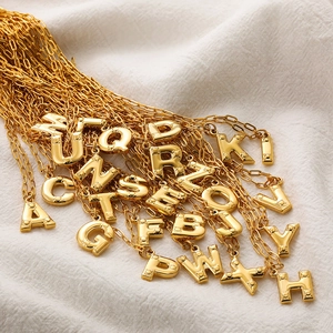 Detailed view of 3D bubble gold initial pendants with studded texture on fabric