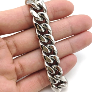 Macro shot of polished silver stainless steel Cuban link bracelet with vine clasp detail