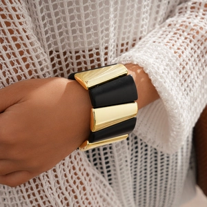 Detail of chunky geometric acrylic stretch bracelet with gold and black matte panels