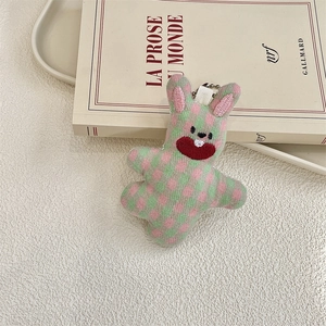 Detail of cute checkered fabric bunny keychain with silver bead chain on a book background