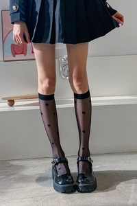 Detail of sheer knee-high socks featuring black heart patterns and Mary Jane shoes