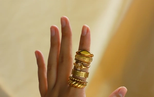 Close-up of vintage gold-plated stackable ring set with multiple textured designs on a finger
