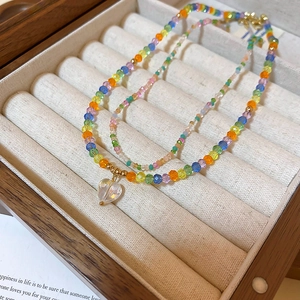 Detail of double-layer beaded necklace featuring colorful beads and a clear heart pendant