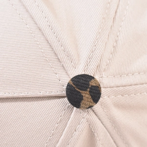 Detailed macro view of the leopard print top button and beige cotton twill stitching